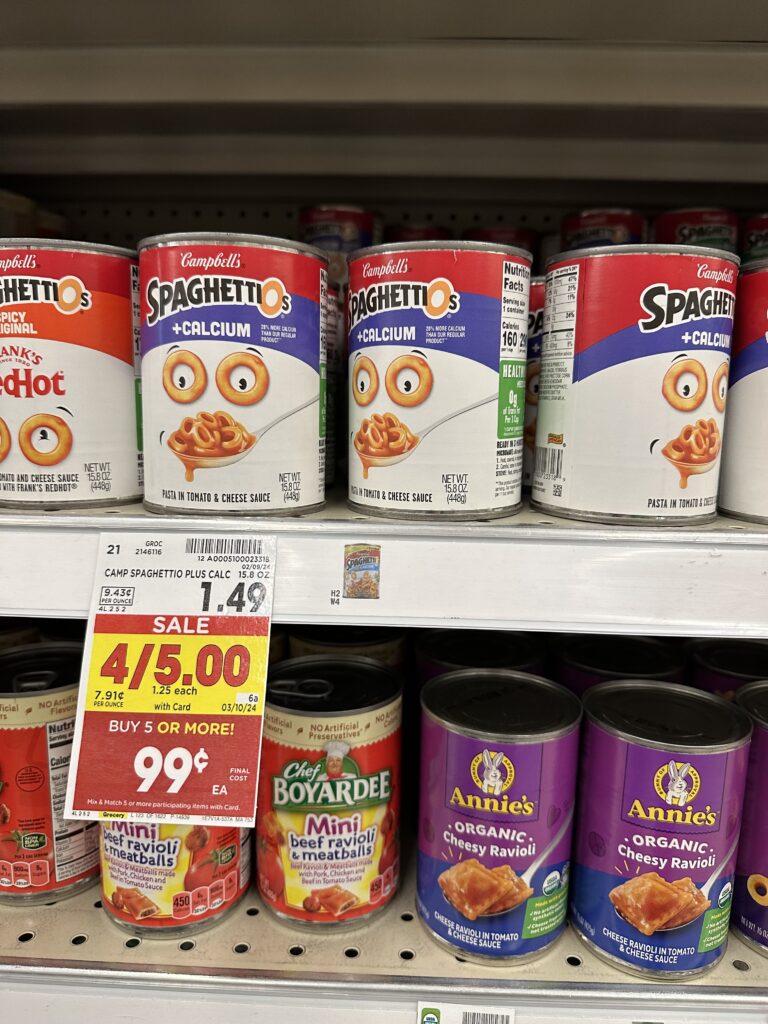 Cans of spaghetti and meatballs on a shelf in a grocery store.